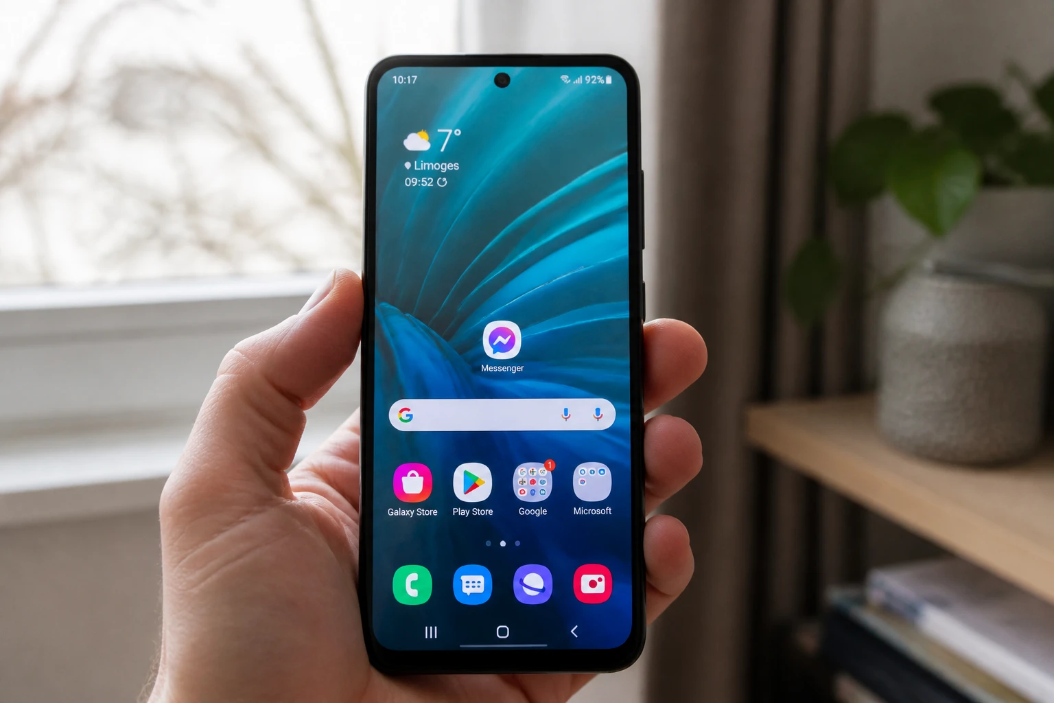 Smartphone Android affichant l'icône Messenger sur l'écran d'accueil, tenu à la main